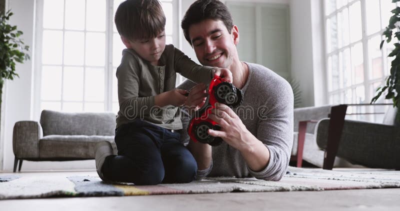 Skupiony mały chłopiec uczący się naprawiać ciężarówkę z ojcem.