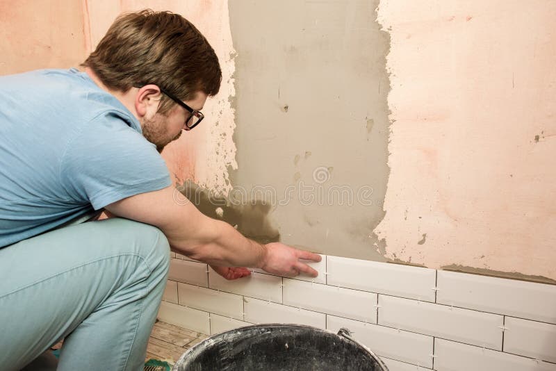 Skupiony tiler kładzie płytki na ścianie łazienki. naprawy domu.