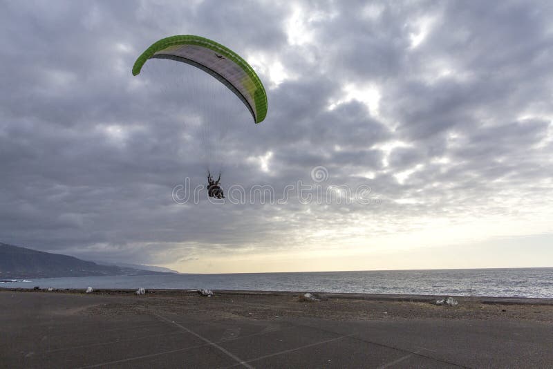 Skydiver en el cielo Silueta del paracaídas en fondo de la puesta del sol Skydiver en la playa del la Cruz Tenerife de Puerto de fotografía de archivo Skydiver en el cielo Silueta del paracaídas en fondo de la puesta del sol Skydiver en la playa del la Cruz Tenerife de Puerto de fotografía de archivo