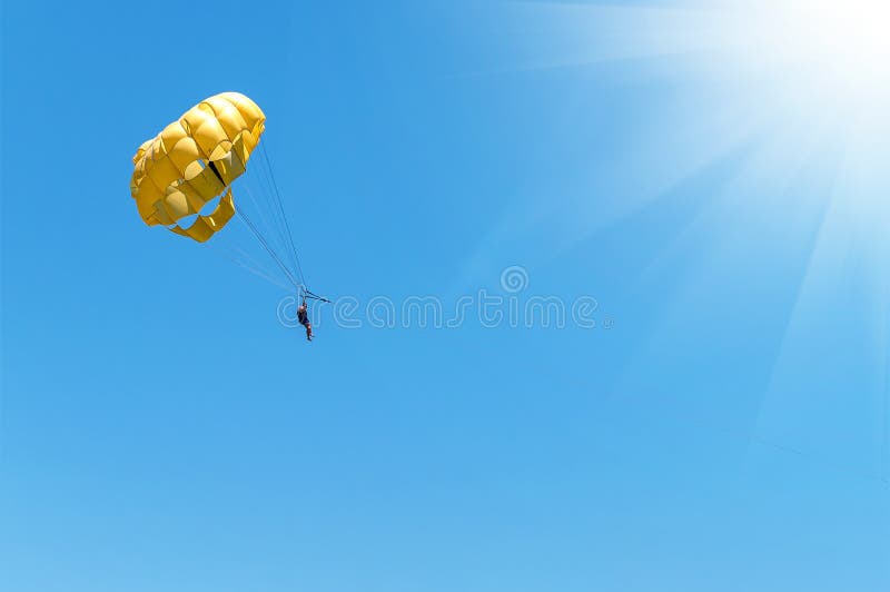 Skydiver Flying with a Yellow Parachute by Speed Boat on Sea. Skydiver