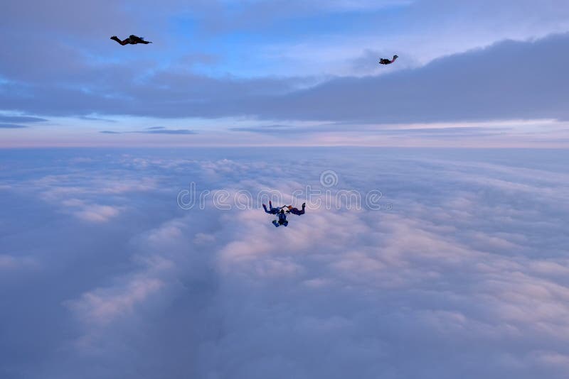 Skydivers faling ovanför rosa moln i solnedgånghimlen royaltyfria foton Skydivers faling ovanför rosa moln i solnedgånghimlen royaltyfria foton