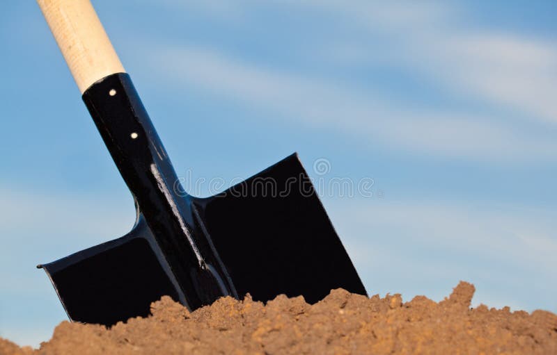 Shovel in the heap of ground against blue sky. Shovel in the heap of ground against blue sky