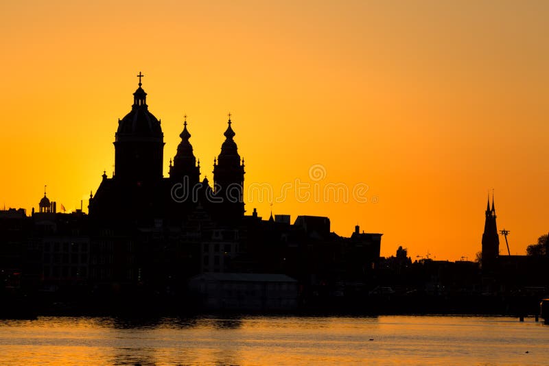 Skyline da arquitetura da cidade de Amsterdão com a igreja de Saint Nicholas Sint-Nicolaaskerk durante o por do sol Pitoresco de imagem de stock Skyline da arquitetura da cidade de Amsterdão com a igreja de Saint Nicholas Sint-Nicolaaskerk durante o por do sol Pitoresco de imagem de stock