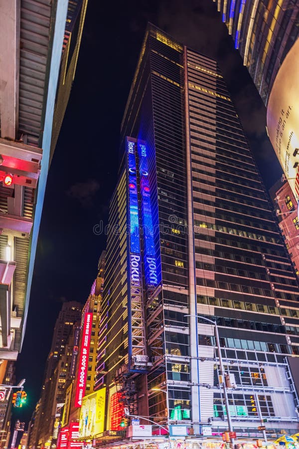 Skyscraper at night in Times Square with illuminated digital signs and advertisements, including glowing Roku display. stock photo