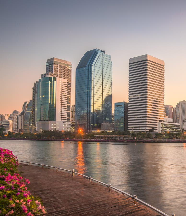 Skyscrapers and Lake with Wooden Walk Way in City Park. View of Benjakiti Park at Sunrise. Beautiful Morning Scene of Public Park in Bangkok, Thailand, Asia