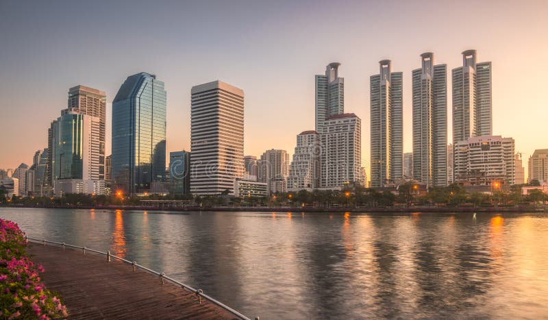 Skyscrapers and Lake with Wooden Walk Way in City Park. View of Benjakiti Park at Sunrise. Beautiful Morning Scene of Public Park in Bangkok, Thailand, Asia