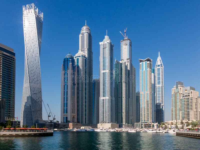 Highrise buildings and yachts in the Marina district of Dubai, United Arab Emirates. The skyscraper called Cayan or Infinity Tower on the left. Highrise buildings and yachts in the Marina district of Dubai, United Arab Emirates. The skyscraper called Cayan or Infinity Tower on the left.