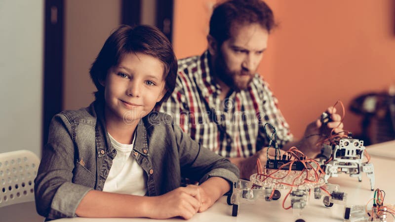 Skäggig fader och son som hemma konstruerar roboten royaltyfri fotografi Skäggig fader och son som hemma konstruerar roboten royaltyfri fotografi