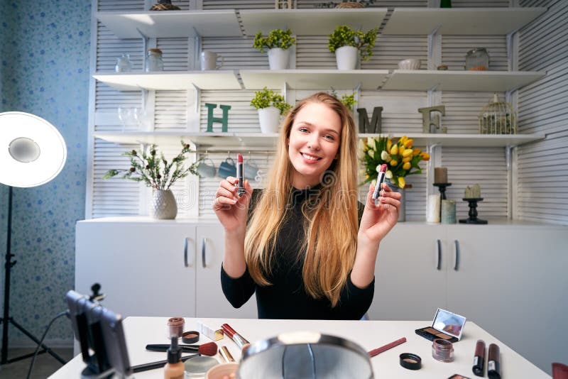 Skönhetsbloggare som filmar daglig makeup-rutin i närheten av kamera på tripod. Inflytelserika, blonde flicka direktuppspelning royaltyfri fotografi