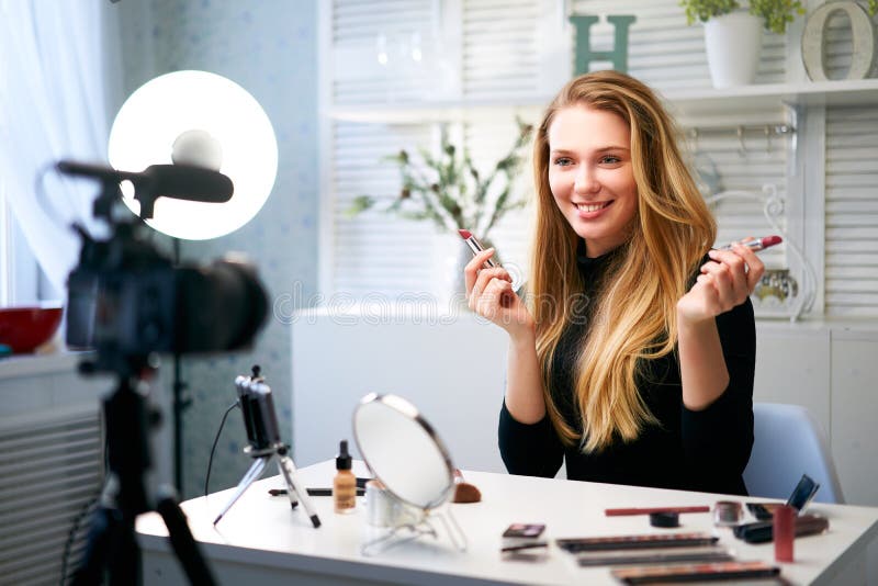 Skönhetsbloggare som filmar daglig makeup-rutin i närheten av kamera på tripod. Inflytelserika, blonde flicka direktuppspelning arkivbild