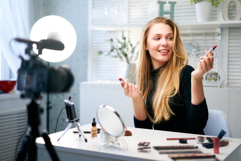 Skönhetsbloggare som filmar daglig makeup-rutin i närheten av kamera på tripod. Inflytelserika, blonde flicka direktuppspelning royaltyfria foton