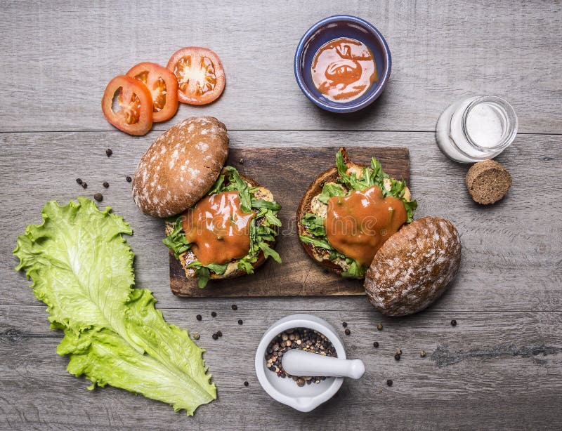 Składniki dla gotować hamburger z kurczakiem, warzywa, pieprze, pomidory, sałata i sól na drewnianym nieociosanym tło wierzchołku zdjęcie stock Składniki dla gotować hamburger z kurczakiem, warzywa, pieprze, pomidory, sałata i sól na drewnianym nieociosanym tło wierzchołku zdjęcie stock