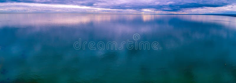 Slaap lage wolken die in kalm oceaanwater reflecteren stock foto Slaap lage wolken die in kalm oceaanwater reflecteren stock foto