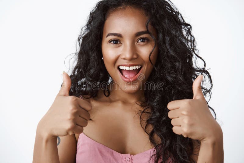 Close-up shot enthusiastic and charismatic good-looking african american girl look upbeat, show thumbs-up gesture and smiling broadly, approve great plan, encourage friend, white background. Close-up shot enthusiastic and charismatic good-looking african american girl look upbeat, show thumbs-up gesture and smiling broadly, approve great plan, encourage friend, white background.