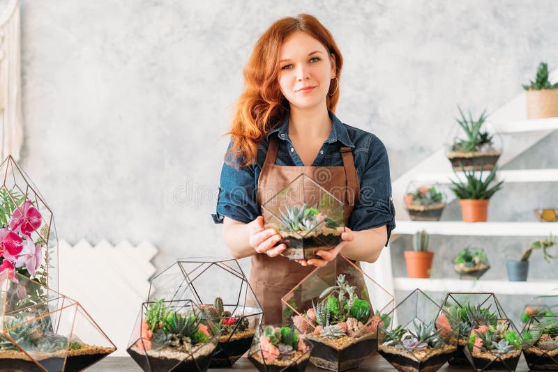 Floral interior decor workshop. Woman holding glass vase with succulents growing in glass vase. Floral interior decor workshop. Woman holding glass vase with succulents growing in glass vase.