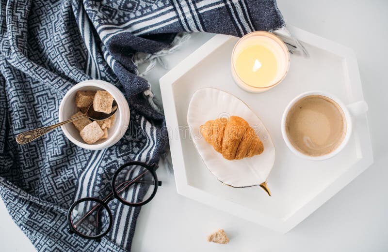 Slags tvåsittssoffahemfrukosten, värme filten, kaffe och gifflet på vit arkivbild Slags tvåsittssoffahemfrukosten, värme filten, kaffe och gifflet på vit arkivbild