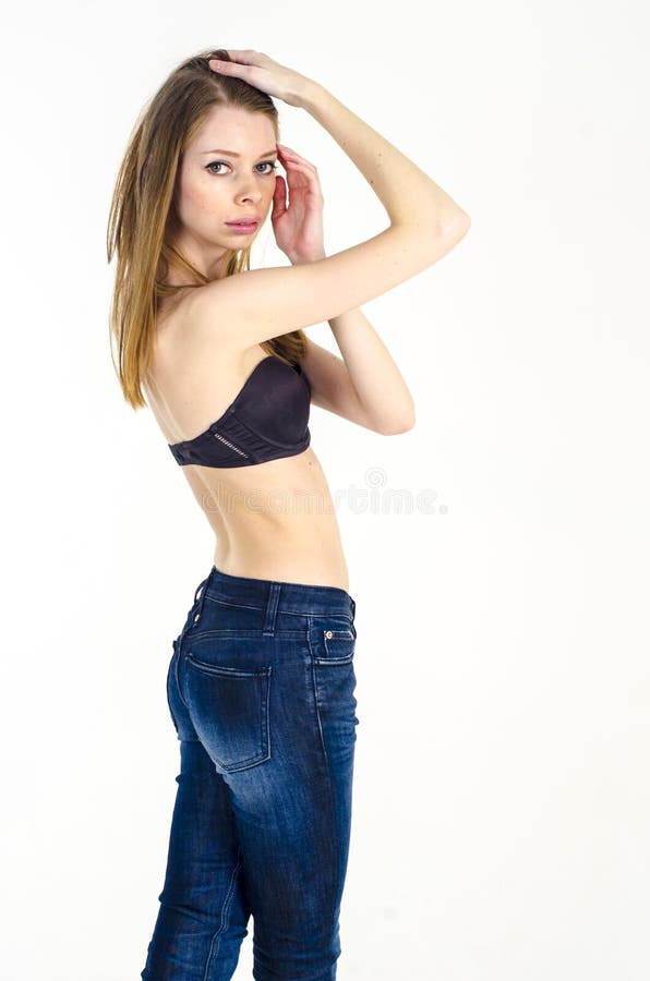 Slank blond flicka med långt hår i jeans och svart behå fotografering för bildbyråer Slank blond flicka med långt hår i jeans och svart behå fotografering för bildbyråer