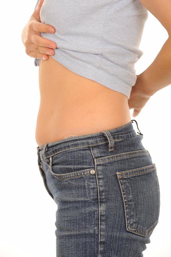 Side view of body of young woman lifting top to show slim stomach or tummy, white background. Side view of body of young woman lifting top to show slim stomach or tummy, white background.