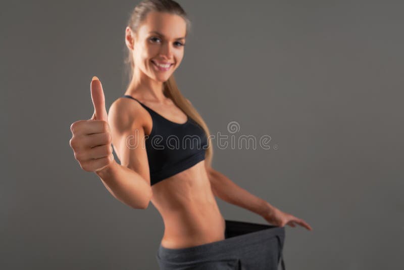 Slanke jonge vrouw die oude grote broek dragen, die succesvol resultaat van een dieet tonen - gewichtsverlies, vermageringsdieetc royalty-vrije stock foto Slanke jonge vrouw die oude grote broek dragen, die succesvol resultaat van een dieet tonen - gewichtsverlies, vermageringsdieetc royalty-vrije stock foto