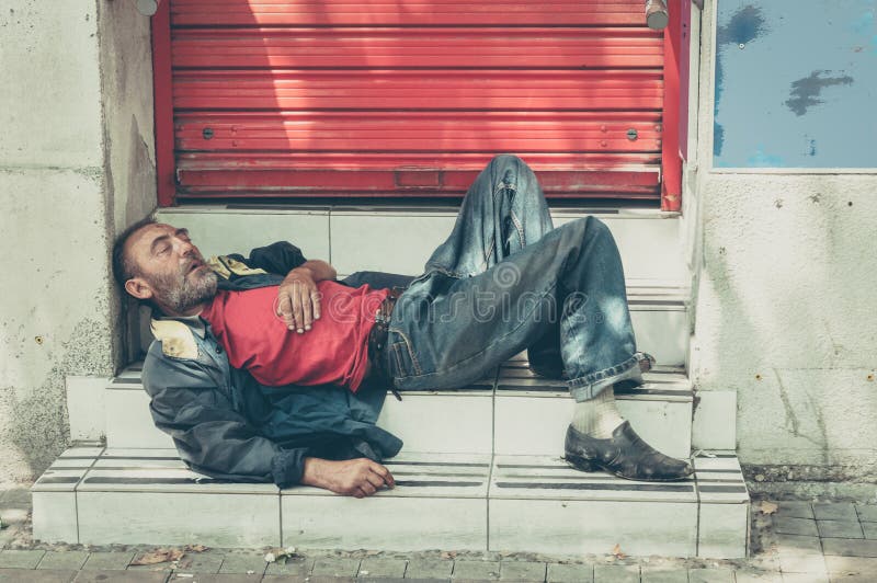 Slechte dakloze mens of vluchtelingsslaap op de treden op de straat, sociaal documentair concept royalty-vrije stock afbeeldingen Slechte dakloze mens of vluchtelingsslaap op de treden op de straat, sociaal documentair concept royalty-vrije stock afbeeldingen