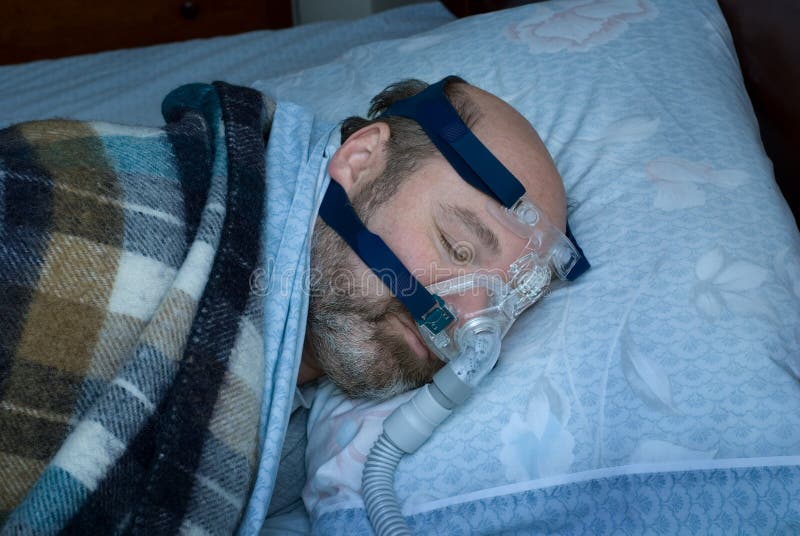 Zralý muž (fotograf je model) spí na boku pomocí cpap nosní maska pro léčbu spánkové apnoe.