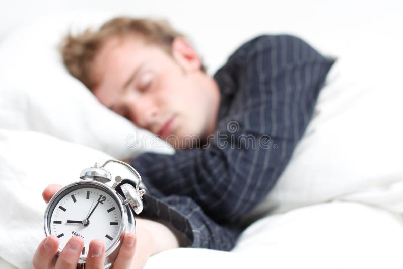 A man sleeping and holding an alarm clock