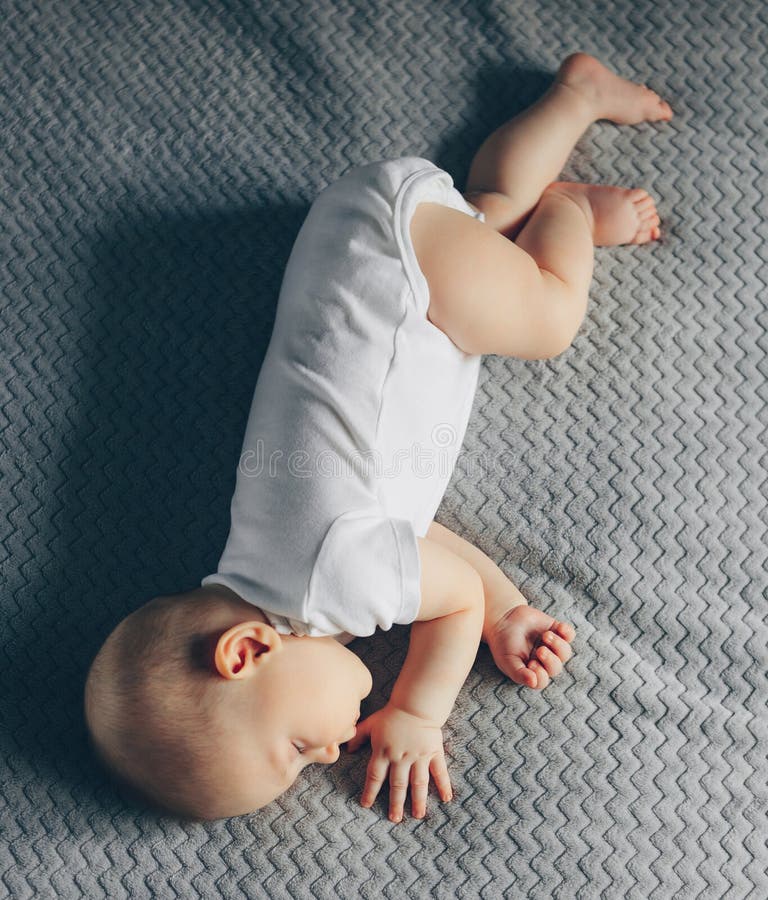 Sleeping Baby Boy in White Bodysuit in Bed with Copyspace Stock Photo