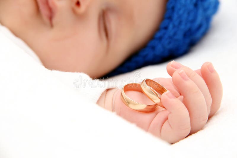 Sleeping baby with wedding rings in hand