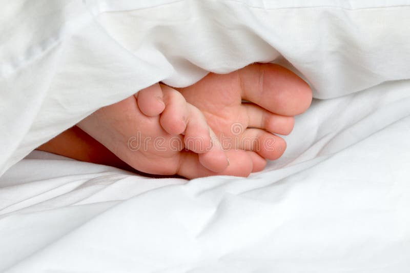 A sleeping child s feet in bedding