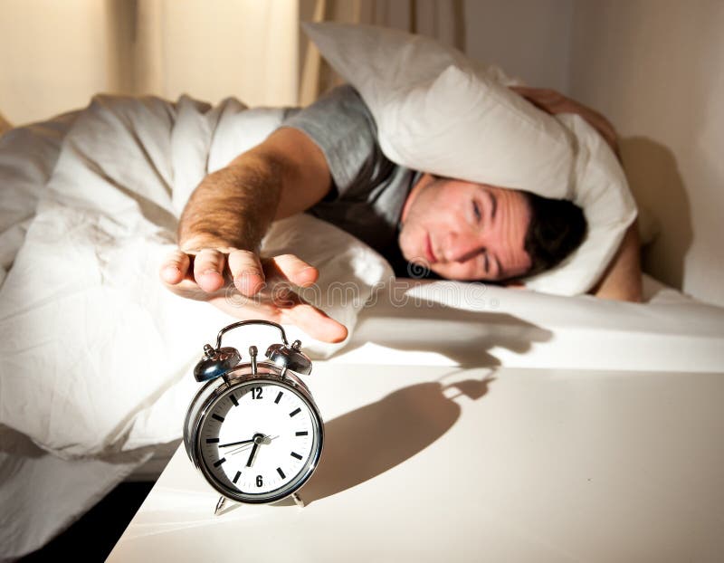 Sleeping man disturbed by alarm clock early mornin