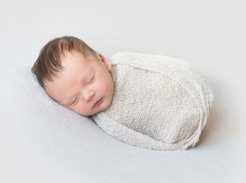 Lovely baby sleeping swaddled in a wrap, close-up royalty free stock photography Lovely baby sleeping swaddled in a wrap, close-up royalty free stock photography