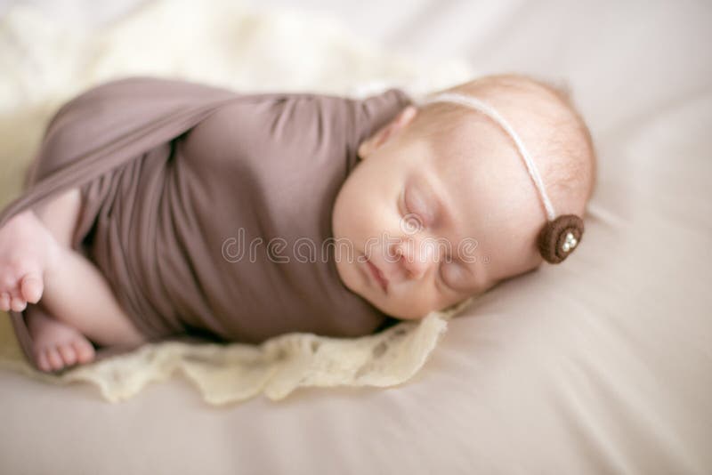 Sleeping Newborn Baby in a Wrap Brown Blanket on Bed Stock Image