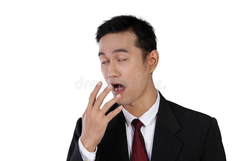 Young Asian businessman yawning with sleepy eyes and his hand covering his opened mouth, isolated on white background. Young Asian businessman yawning with sleepy eyes and his hand covering his opened mouth, isolated on white background