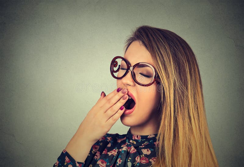 It is too early for meeting. Closeup portrait sleepy young woman with wide open mouth yawning eyes closed looking bored isolated on gray wall background. Face expression emotion body language