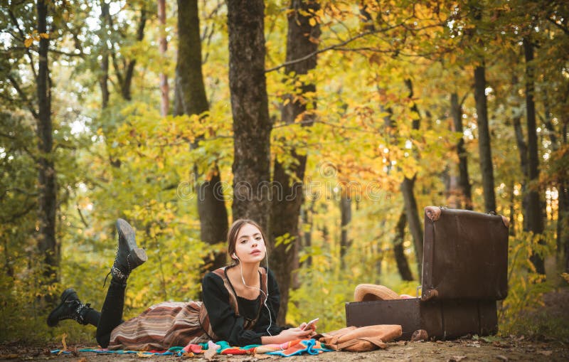Slender beautiful young woman rests in the autumn in the park. Enjoying music and picnicking. Vintage picnic accessories royalty free stock photos Slender beautiful young woman rests in the autumn in the park. Enjoying music and picnicking. Vintage picnic accessories royalty free stock photos