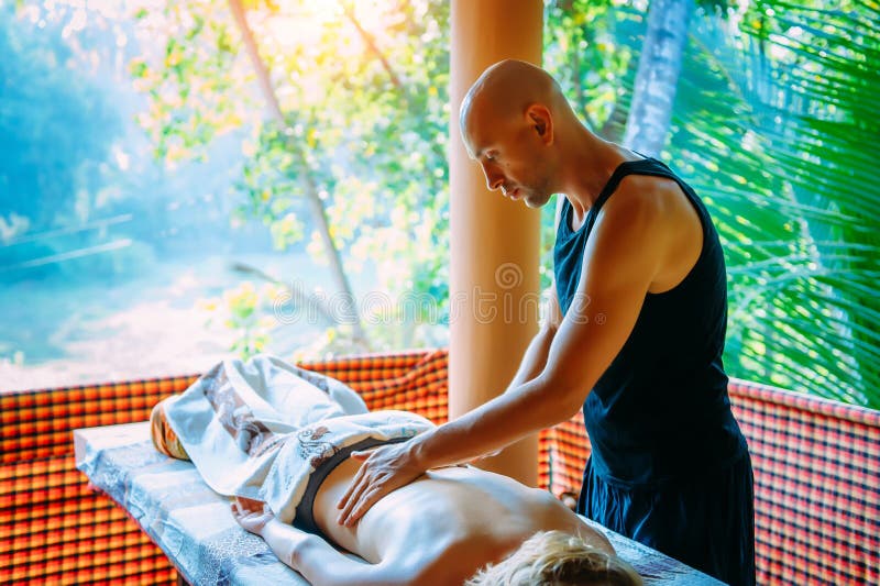 A Man Masseur Does A Massage Of The Thigh And Lower Leg To A Woman Client In A Dark Room Of The