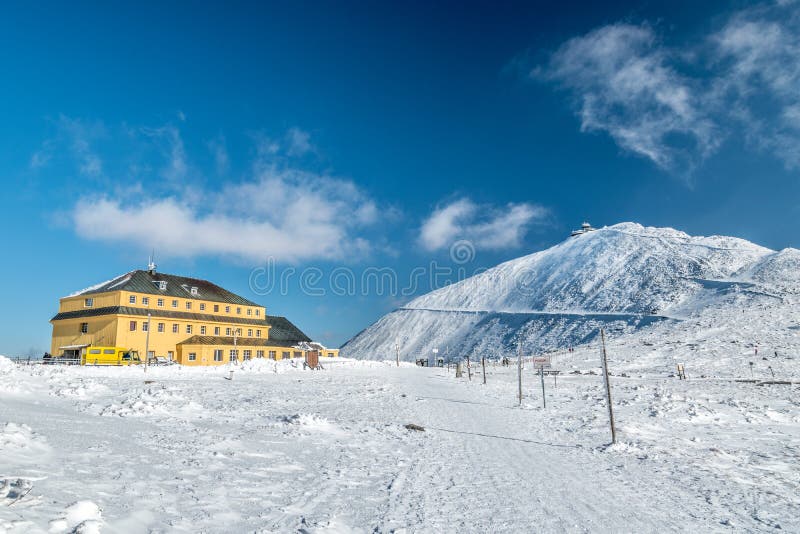 Slezsky dum Slaski dom mountain hut with Snezka peak in behind on a sunny day in winter, Krkonose mountains, Poland-Czech