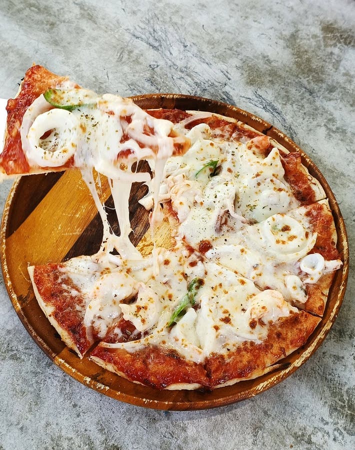 A slice of crispy pizza with seafood and cheese (Selective Focus stock image