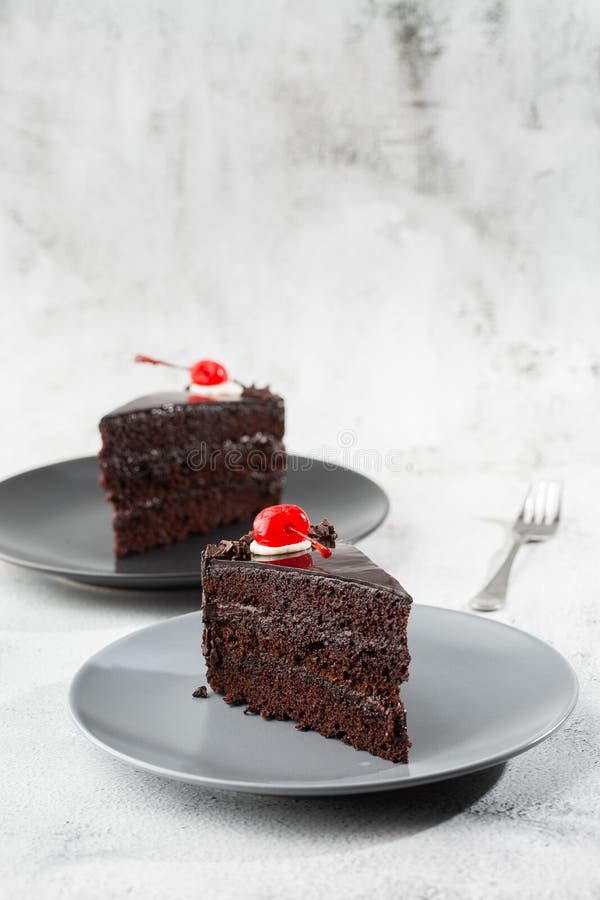 A slice of delicious chocolate cake with cherry on top on marble background. Piece of Cake on a Plate. Sweet food. Sweet