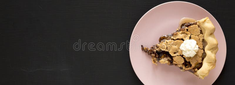 A slice of homemade Chocolate Walnut Derby Pie on a pink plate on a black surface, top view. Overhead, from above, flat lay. Copy