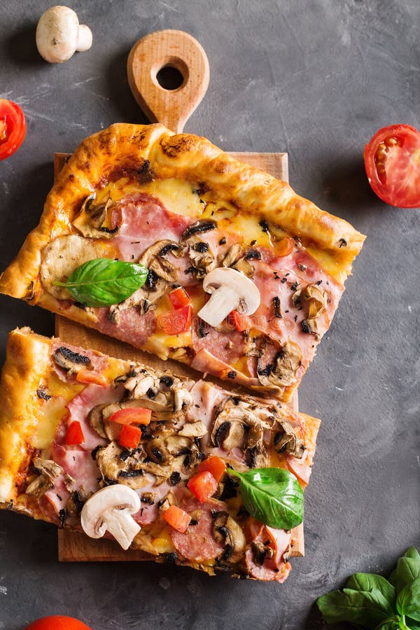 Slice of Square Pizza with Basil Tomatoes and Mushrooms on a Wooden