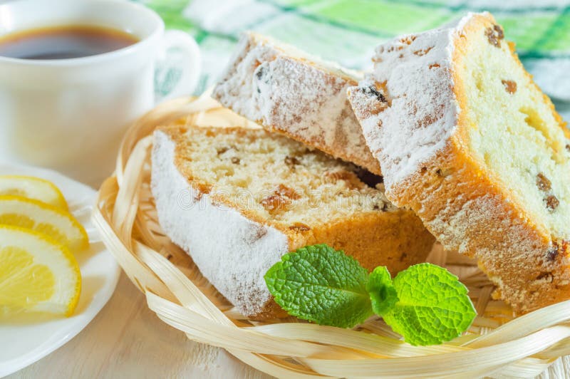 Sliced biscuit cake, a cup of tea, lemon slices and mint leaves. Delicious breakfast or dessert. Three slices of biscuit cake with raisins on a wicker plate royalty free stock images Sliced biscuit cake, a cup of tea, lemon slices and mint leaves. Delicious breakfast or dessert. Three slices of biscuit cake with raisins on a wicker plate royalty free stock images