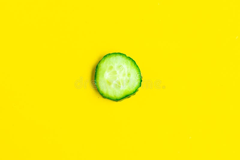 Sliced cucumber on bright yellow background.