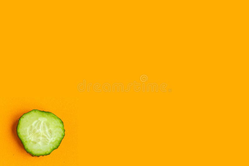 Sliced fresh cucumber isolated on orange background, top view, minimal concept, copy space