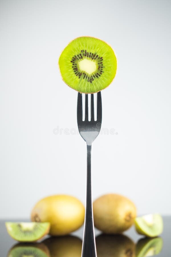 Sliced fresh and juicy green kiwi on the fork with whole kiwi in