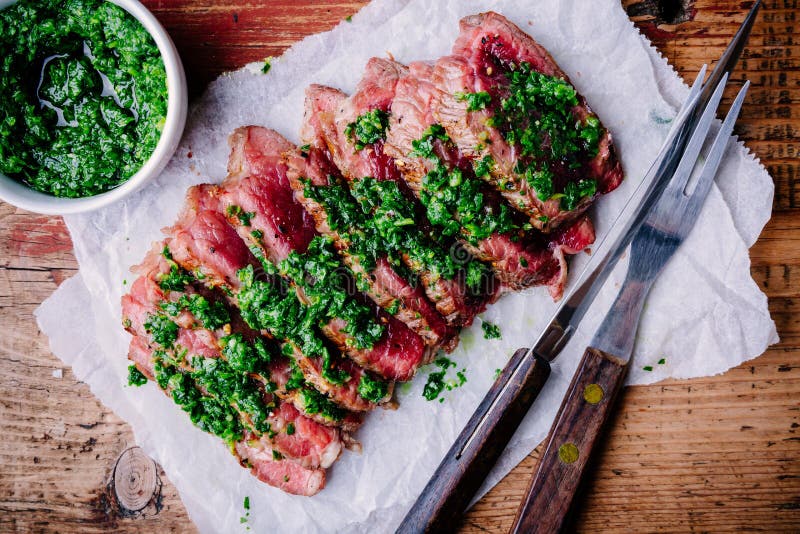 Sliced grilled barbecue beef steak with green chimichurri sauce royalty free stock photo Sliced grilled barbecue beef steak with green chimichurri sauce royalty free stock photo
