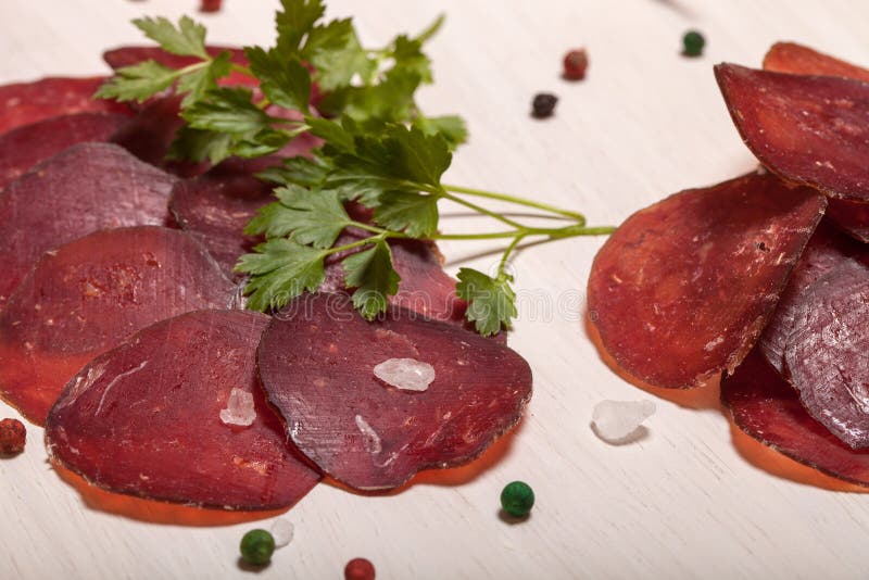 Sliced horse sausage, herbs and spices on cutting board. Selective focus