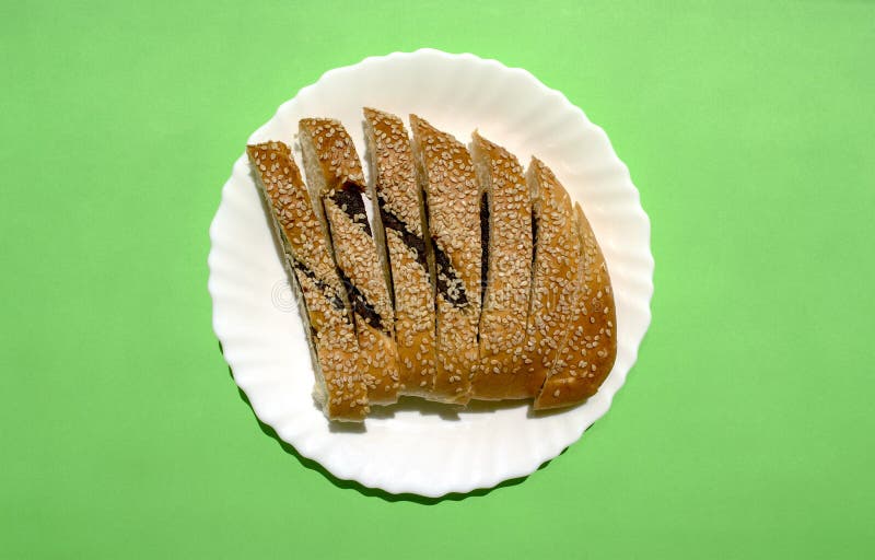 Sliced Ma\ arook bread with date fruit and sesame seeds in white plate on green background