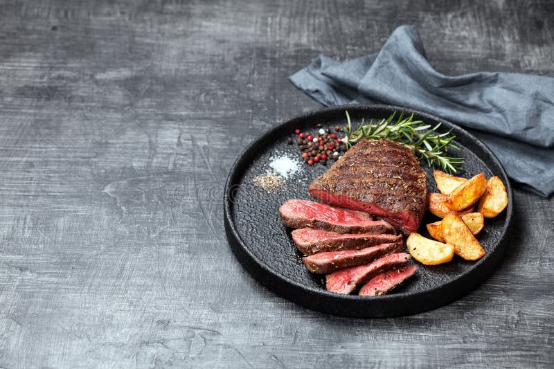 Sliced medium rare grilled beef steak and potato wedges