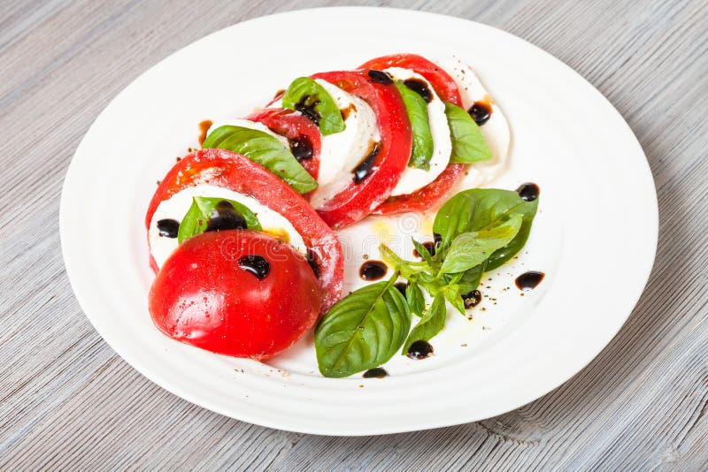 Sliced mozzarella and tomato with basil leaves